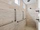 Accessible shower featuring grab bars and a showerhead, tiled in beige stone-look tiling at 10127 Knotty Skye Ave, Las Vegas, NV 89166