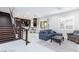 Bright and airy living room connected to kitchen with staircase, modern furnishings, and white floors at 10356 Addie De Mar Ln, Las Vegas, NV 89135