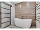 Stylish bathroom featuring a soaking tub with wood-look tile accent wall and decorative tile flooring at 10520 Maystar Ln, Las Vegas, NV 89135