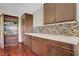 Kitchenette with custom cabinets, mosaic tile backsplash, and wood floors at 10520 Maystar Ln, Las Vegas, NV 89135