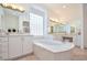 Large Primary bathroom features a deep soaking tub, dual sinks, custom lighting, and tile floors at 10573 Bambola Pl, Las Vegas, NV 89135