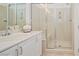 Bathroom with neutral tile, and a glass enclosed shower with a built-in seat sits next to a vanity with white countertops at 10573 Bambola Pl, Las Vegas, NV 89135