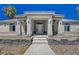 Close up of the front entrance featuring an arched entryway, pillars and desert landscaping at 1420 Logandale Dr, Logandale, NV 89021