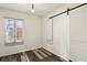 Bright bedroom with wood-look flooring, a window with blinds, and a sliding barn door at 1844 Yale St, North Las Vegas, NV 89030