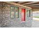 A close exterior shot of the house with the red front door and the stone facade and green painted window frames at 1844 Yale St, North Las Vegas, NV 89030