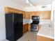 A kitchen is featured with wood cabinets, white countertops and black appliances with a tiled floor at 2110 Los Feliz St # 1083, Las Vegas, NV 89156