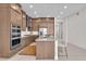 Kitchen with brown cabinets, stainless steel appliances, double oven, hood vent, and island with seating at 4153 Solace St, Las Vegas, NV 89135