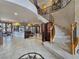 Open-concept living space with a curved staircase, tile flooring, and views of the dining and seating areas at 5445 Pendini Point Ct, Las Vegas, NV 89141
