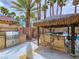 Outdoor kitchen with built-in grill, bar, and shaded seating area by palm trees at 5445 Pendini Point Ct, Las Vegas, NV 89141