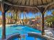 Beautiful pool featuring a rock waterfall and a tiki hut covered hot tub surrounded by palm trees at 5445 Pendini Point Ct, Las Vegas, NV 89141
