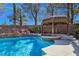 Lush backyard features a sparkling pool with a rock waterfall and a tiki hut covered hot tub at 5445 Pendini Point Ct, Las Vegas, NV 89141