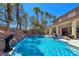 Beautiful pool with waterfall feature and mature trees, seamlessly blending luxury and natural beauty at 5445 Pendini Point Ct, Las Vegas, NV 89141