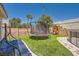 Fenced backyard includes a trampoline, swing set, and lounge seating on artificial turf at 5638 Wild Olive St, Las Vegas, NV 89118