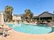 Community pool with lounge chairs, tables, and umbrellas surrounded by well-maintained landscaping at 5710 E Tropicana Ave # 1055, Las Vegas, NV 89122