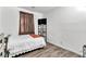 Simple bedroom features a bed, wood-look flooring, TV, and a window with brown curtains at 6829 Painted Morning Ave, Las Vegas, NV 89142
