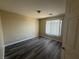 A simple bedroom features dark laminate flooring, neutral paint, and a window with vertical blinds at 7929 Valladolid Ave, Las Vegas, NV 89178
