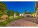 Landscaped backyard with putting green, brick pavers, mature trees, and perimeter wall at 8126 Majestic Bighorn St, Las Vegas, NV 89166