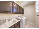 Well-equipped laundry room with dark wood cabinets, sink, and modern washer and dryer at 8126 Majestic Bighorn St, Las Vegas, NV 89166