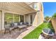 Covered patio with comfortable seating and a view of the landscaped backyard and lush artificial turf at 8126 Majestic Bighorn St, Las Vegas, NV 89166