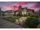 Inviting home exterior featuring a lush lawn, stone walkway, and mature landscaping at dusk at 8316 Vibrant Dr, Las Vegas, NV 89117