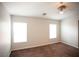 A spacious bedroom with two bright windows, neutral walls, ceiling fan, and plush brown carpet at 9526 Borough Park St, Las Vegas, NV 89178