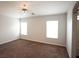 A bright bedroom featuring neutral walls, two windows, ceiling fan, and plush brown carpet at 9526 Borough Park St, Las Vegas, NV 89178