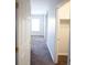 A hallway with gray carpet runs towards a bright window, offering a glimpse into the well-lit interior of the home at 9526 Borough Park St, Las Vegas, NV 89178