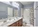 Neutral bathroom featuring double sinks, wooden cabinets, a large mirror, and a shower-tub combination at 9822 Opal Bridge Ct, Las Vegas, NV 89178