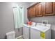 Efficient laundry room with modern washer and dryer, upper cabinets, and a laundry basket for convenience at 9822 Opal Bridge Ct, Las Vegas, NV 89178