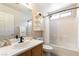 Well-lit bathroom with a shower-tub combo, wood vanity, and white tile, offering a refreshing and clean space at 10254 Martinsburg Ct, Las Vegas, NV 89183
