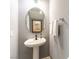 Stylish powder room featuring a pedestal sink, oval mirror, neutral paint, and modern fixtures, creating a clean, updated look at 10254 Martinsburg Ct, Las Vegas, NV 89183