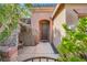 Inviting home entrance with stone facade, arched doorway, and lush landscaping at 10310 Songsparrow Ct, Las Vegas, NV 89135