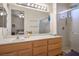 Bathroom featuring a large mirror, wood cabinets, and glass door walk-in shower at 10720 Sky Meadows Ave, Las Vegas, NV 89134
