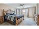 Spacious bedroom with a rustic wood bed frame, ceiling fan, and large windows for natural light at 10744 Yarmouth Bay Ct, Las Vegas, NV 89179