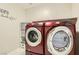 Laundry room showcasing modern red washer and dryer set with ample shelving at 10744 Yarmouth Bay Ct, Las Vegas, NV 89179