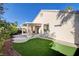 Back exterior featuring stucco walls, covered patio, artificial lawn, and manicured shrubs at 1506 Camino Summit Ave, Henderson, NV 89012