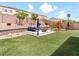 Landscaped backyard featuring artificial turf, a tiered seating area, and a play set at 1604 Patrick Thomas Ct, North Las Vegas, NV 89086