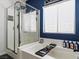 Modern bathtub and shower featuring glass doors, blue accent wall and natural light at 1604 Patrick Thomas Ct, North Las Vegas, NV 89086