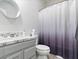 Bathroom with marble countertop, gray vanity, round mirror, and shower with a purple and white ombre curtain at 1604 Patrick Thomas Ct, North Las Vegas, NV 89086