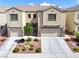 Townhouse exterior with two-car garages, a small tree, and desert landscaping at 1604 Patrick Thomas Ct, North Las Vegas, NV 89086
