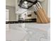 Close-up of white marble kitchen countertop, complemented by stainless steel gas range at 2029 Poppywood Ave, Henderson, NV 89012