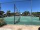 Community tennis court enclosed with a chain link fence and shade trees in the background at 225 Greenbriar Townhouse Way, Las Vegas, NV 89121