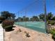 Community tennis court surrounded by a fence, green trees and bushes at 225 Greenbriar Townhouse Way, Las Vegas, NV 89121