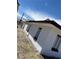 Side view of a charming white house with brown trim, set against a bright blue sky and a gravel yard at 2417 St George St, North Las Vegas, NV 89030
