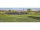 Aerial view of a fenced tennis court surrounded by grass, trees, and distant mountains at 262 Inflection St, Henderson, NV 89011