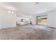 Open concept living area featuring neutral carpet and seamless access to the kitchen and sliding glass doors to the patio at 2767 Lindsey Springs St, Las Vegas, NV 89142