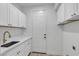 Laundry room features white cabinets, quartz counters, a sink, and a door to the exterior at 2826 Barrow Downs St, Las Vegas, NV 89135