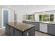 Spacious kitchen with gray cabinets, stone countertops, and an island with sink with views of the backyard pool at 3010 Hammerwood Dr, Las Vegas, NV 89135