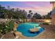 Resort-style pool featuring rock accents, lush landscaping, and a sunken seating area at twilight at 3010 Hammerwood Dr, Las Vegas, NV 89135