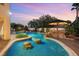 Beautiful swimming pool with rock features, lush landscaping, and a sunken seating area at dusk at 3010 Hammerwood Dr, Las Vegas, NV 89135